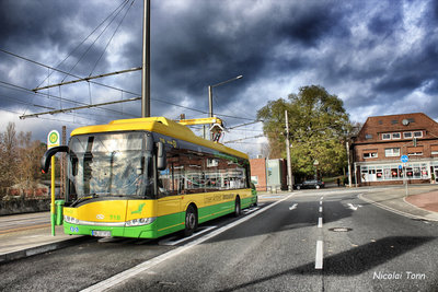 A STOAG bus at a bus stop with dark clouds in the sky