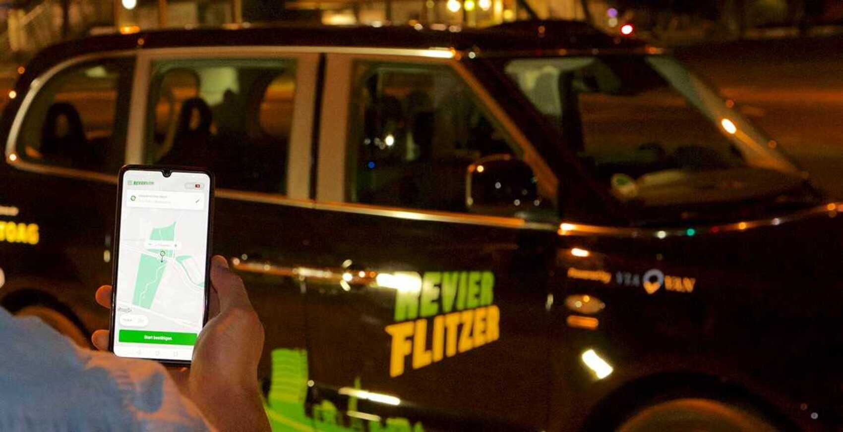 Person schaut auf Smartphone vor dem Revierflitzer der STOAG