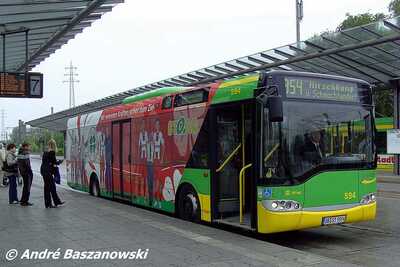 Ein Fahrzeug der STOAG mit SC Rot-Weiß Werbung steht an einem Busbahnhof mit wartenden Personen