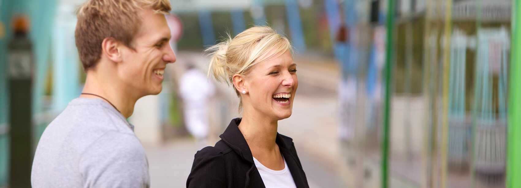 Zwei Personen lachen an der Haltestelle