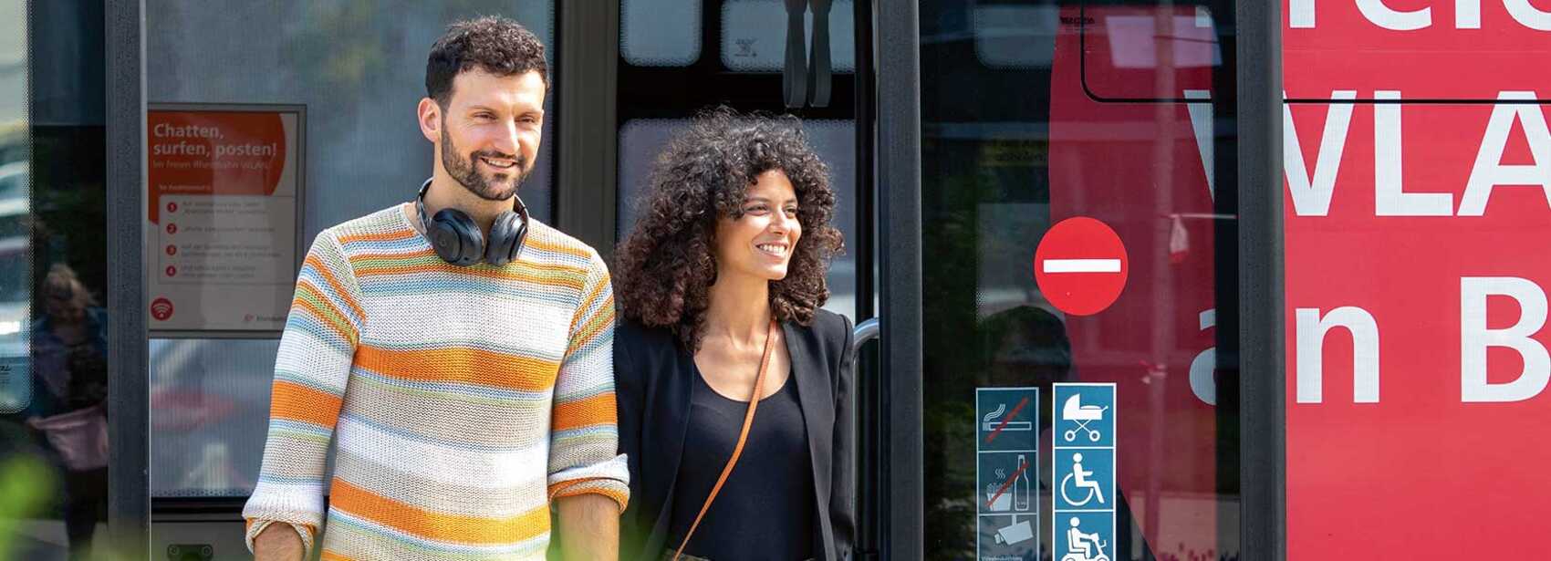 Zwei junge Erwachsene steigen aus dem Bus