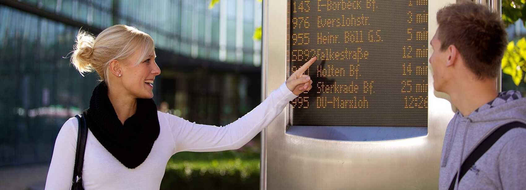 Frau zeigt auf dynamische Fahrgastinformation