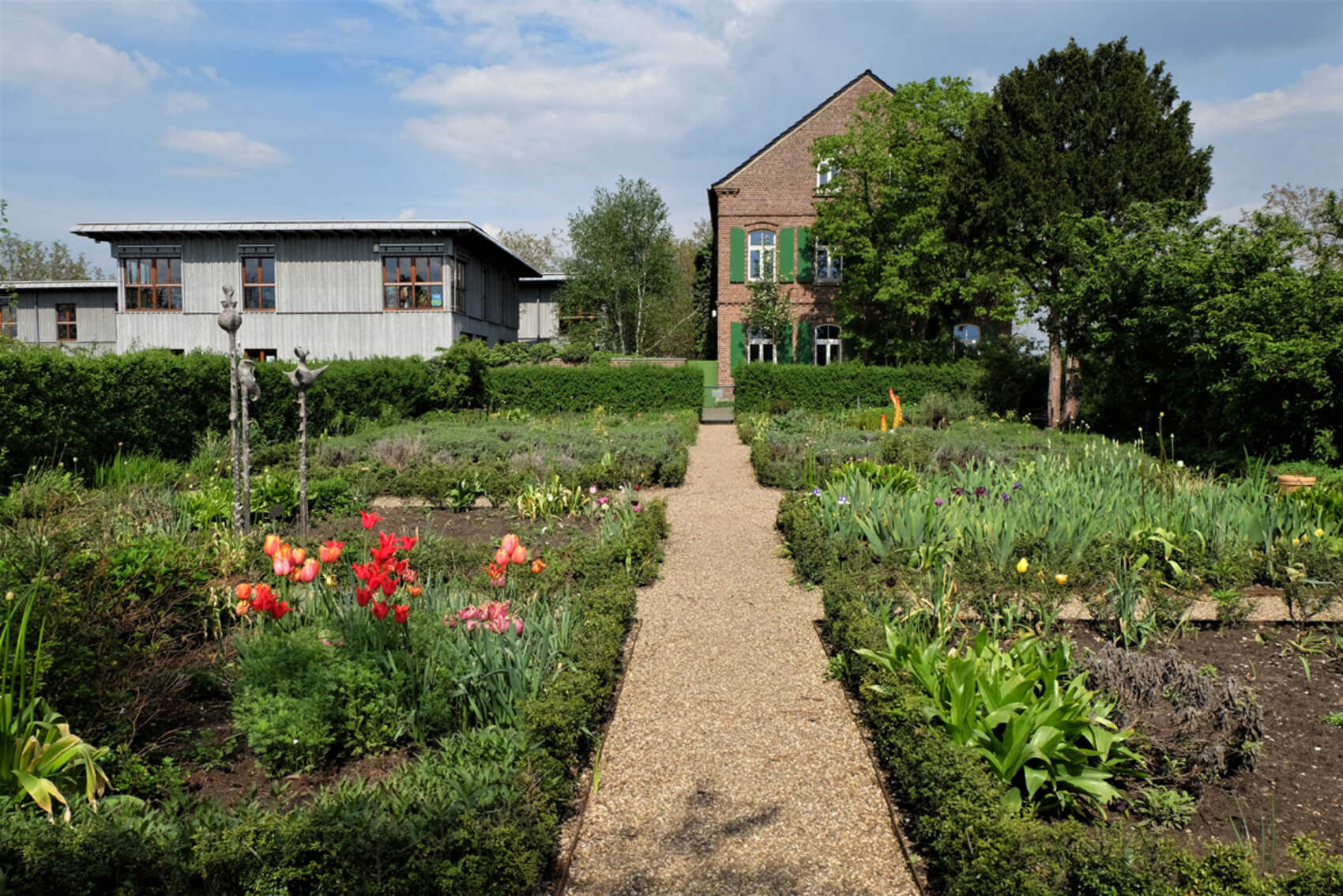 Garten mit blühenden Pflanzen, im Hintergrund Haus Ripshorst